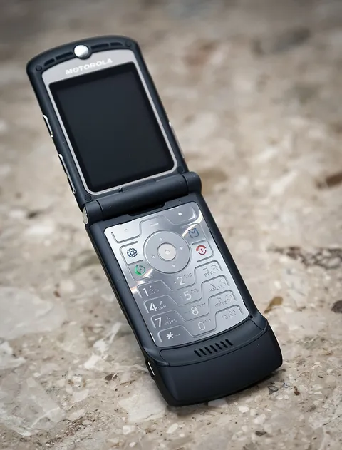 A black Motorola RAZR V3, open, on stone