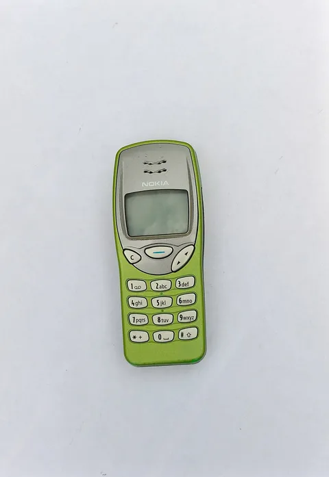 A lime green Nokia 3210 lying on a white surface